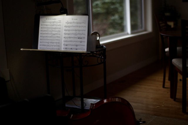 dark room with lit music stand holding sheet music