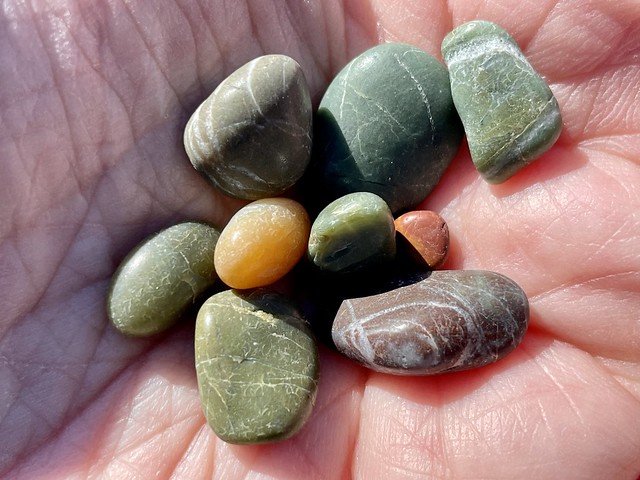 Closeup of a hand holding several colorful rocks with various textures