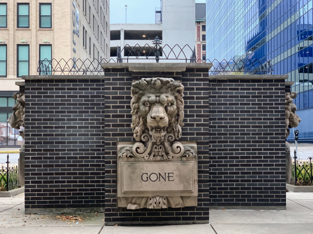 Lion statue on brick memorial with engraved word: gone