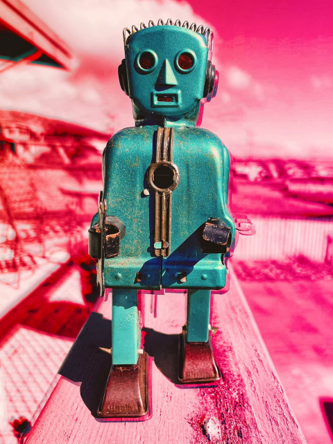 an old wind-up robot toy on a colorful digitally altered background